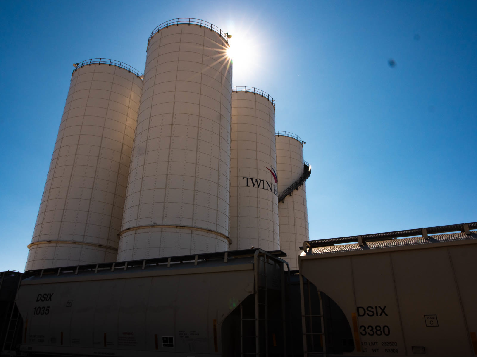 Overhead view of the transload yard: shunt locomotive, tank and hopper cars, dry-bulk silos and truck scale